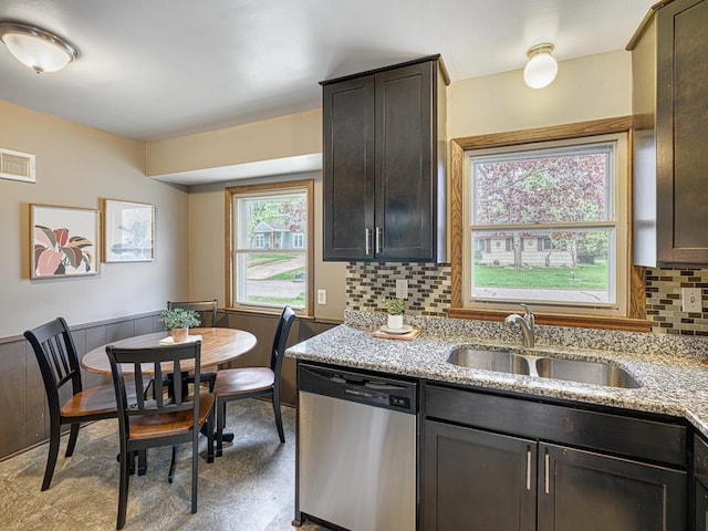 kitchen featuring dishwasher, a sink, tasteful backsplash, light stone countertops, and dark brown cabinetry