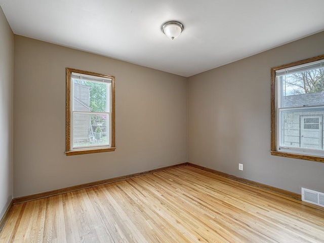 unfurnished room featuring plenty of natural light, light wood finished floors, and baseboards