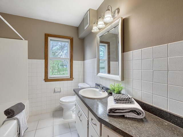 full bath featuring tile walls, toilet, tile patterned floors, vanity, and wainscoting