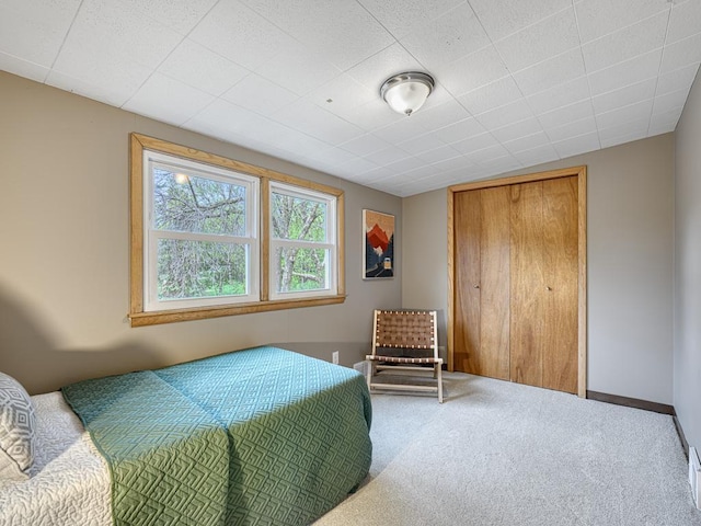 carpeted bedroom featuring a closet and baseboards