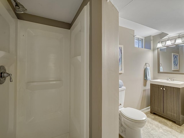bathroom with a shower, toilet, vanity, and baseboards