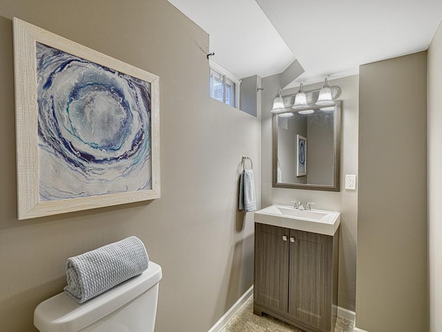 bathroom featuring baseboards, vanity, and toilet
