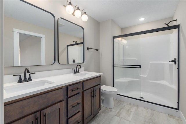 full bath with double vanity, toilet, a sink, and a stall shower