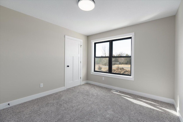 spare room with carpet floors, baseboards, and visible vents