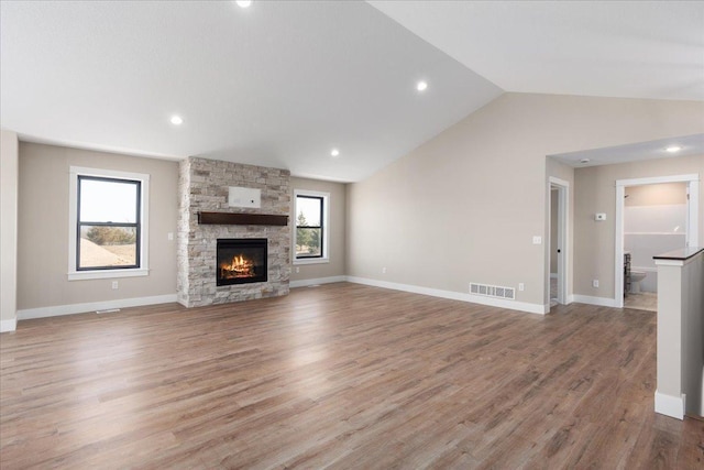 unfurnished living room with visible vents, lofted ceiling, wood finished floors, a fireplace, and baseboards
