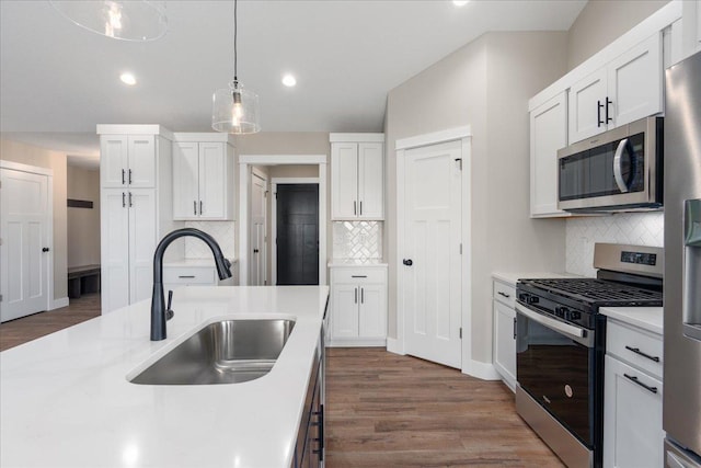 kitchen with light countertops, white cabinetry, a sink, appliances with stainless steel finishes, and backsplash