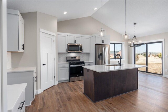kitchen with backsplash, a sink, light countertops, lofted ceiling, and stainless steel appliances