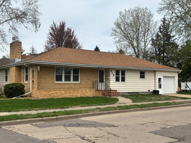 505 Victoria St, Fairmont, MN 56031 - ranch-style home featuring a chimney, brick siding, an attached garage, concrete driveway, and a front lawn