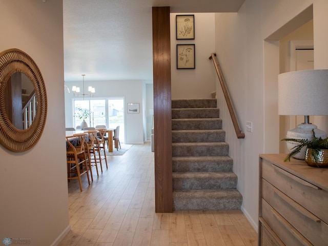 stairs with baseboards, wood finished floors, and a chandelier