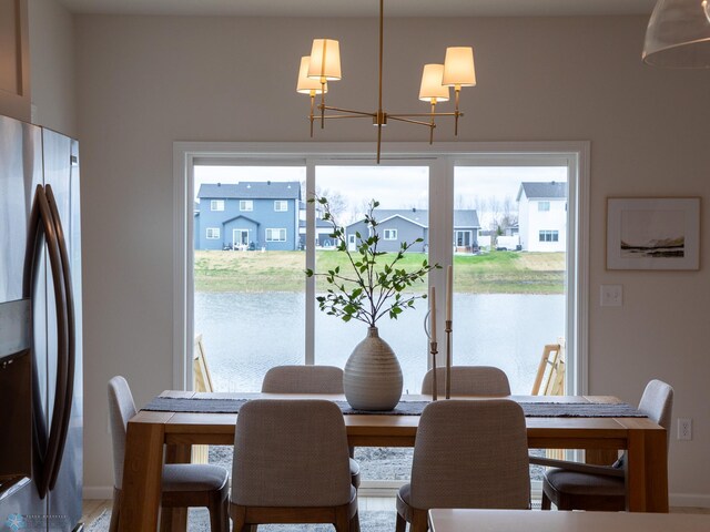 dining area featuring a water view, baseboards, an inviting chandelier, and a residential view