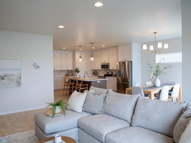 living area featuring recessed lighting, light wood-style flooring, baseboards, and a notable chandelier