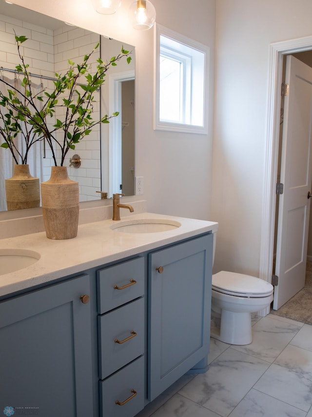 bathroom with double vanity, a sink, marble finish floor, and toilet