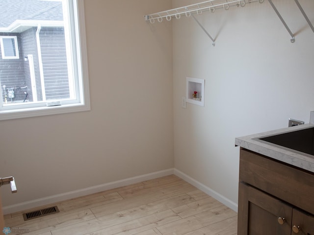 laundry room with washer hookup, visible vents, light wood-type flooring, a sink, and baseboards