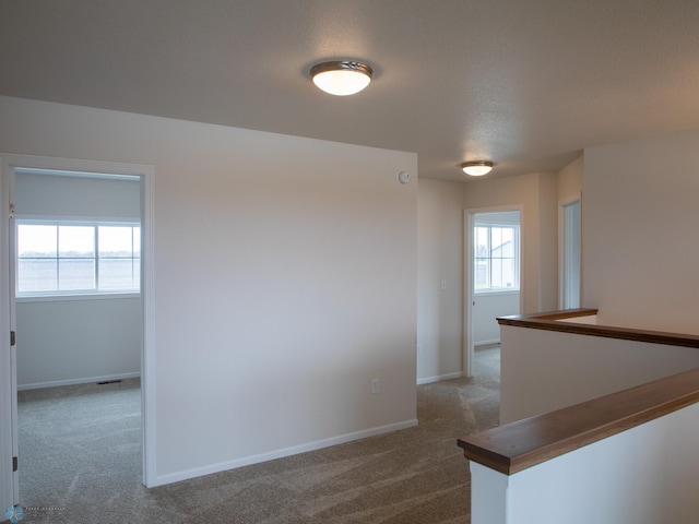 hallway featuring carpet flooring and baseboards