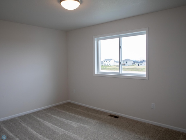 spare room with carpet floors, baseboards, and visible vents