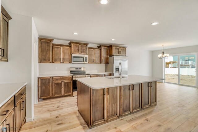 3445 18th St S, Moorhead, MN 56560 - kitchen featuring a sink, light wood finished floors, a chandelier, stainless steel appliances, and a center island with sink