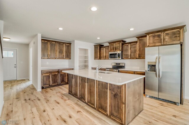 3445 18th St S, Moorhead, MN 56560 - kitchen with a kitchen island with sink, light wood-type flooring, a sink, light countertops, and stainless steel appliances