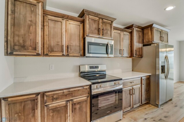 3445 18th St S, Moorhead, MN 56560 - kitchen with light wood-style floors, recessed lighting, light countertops, brown cabinets, and appliances with stainless steel finishes