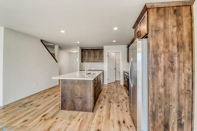 3445 18th St S, Moorhead, MN 56560 - kitchen featuring a sink, light countertops, freestanding refrigerator, light wood-style flooring, and an island with sink