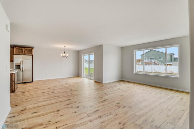 3445 18th St S, Moorhead, MN 56560 - unfurnished living room featuring baseboards, light wood finished floors, and a notable chandelier