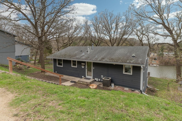 rear view of property with roof with shingles, a yard, and cooling unit