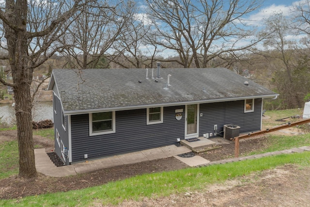 rear view of house with central AC and a shingled roof
