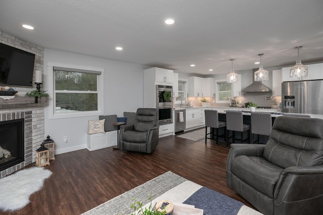 living area featuring dark wood-type flooring, recessed lighting, baseboards, and a brick fireplace