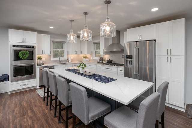kitchen with tasteful backsplash, stainless steel appliances, wall chimney exhaust hood, and white cabinets