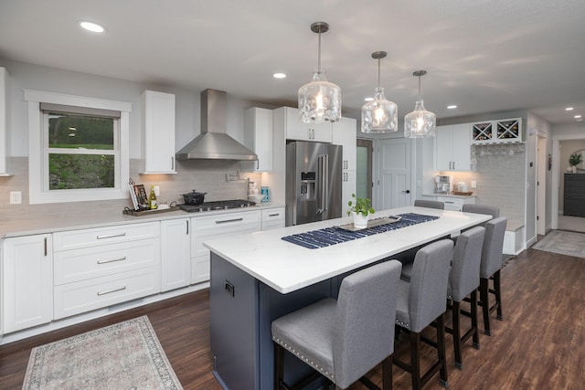 kitchen with high end fridge, wall chimney exhaust hood, backsplash, and dark wood finished floors