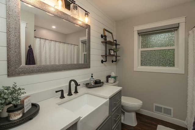 full bath featuring visible vents, vanity, wood finished floors, toilet, and baseboards