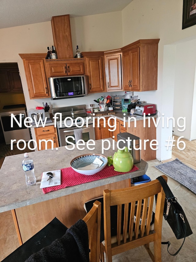 kitchen featuring brown cabinets, stainless steel appliances, and light countertops