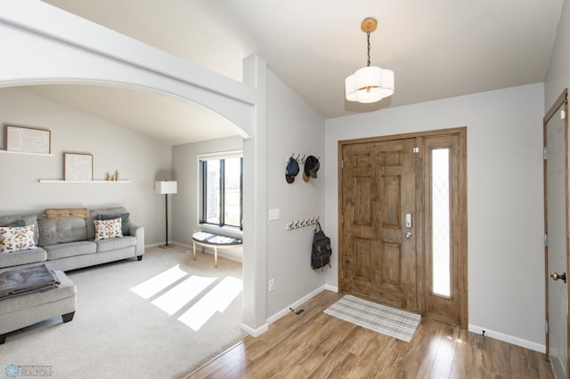 foyer entrance featuring arched walkways, baseboards, and light wood-type flooring