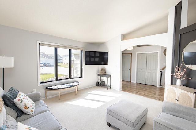 living room with arched walkways, baseboards, lofted ceiling, and carpet