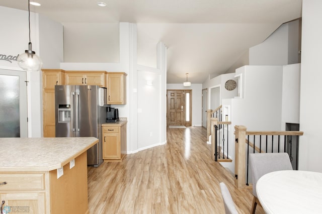 kitchen featuring stainless steel fridge with ice dispenser, light wood-style floors, light countertops, light brown cabinets, and high vaulted ceiling
