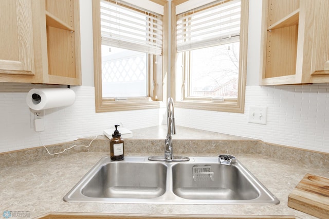 kitchen featuring a sink, decorative backsplash, light brown cabinets, and light countertops