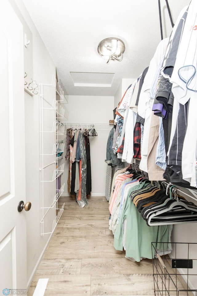 spacious closet with wood finished floors and attic access