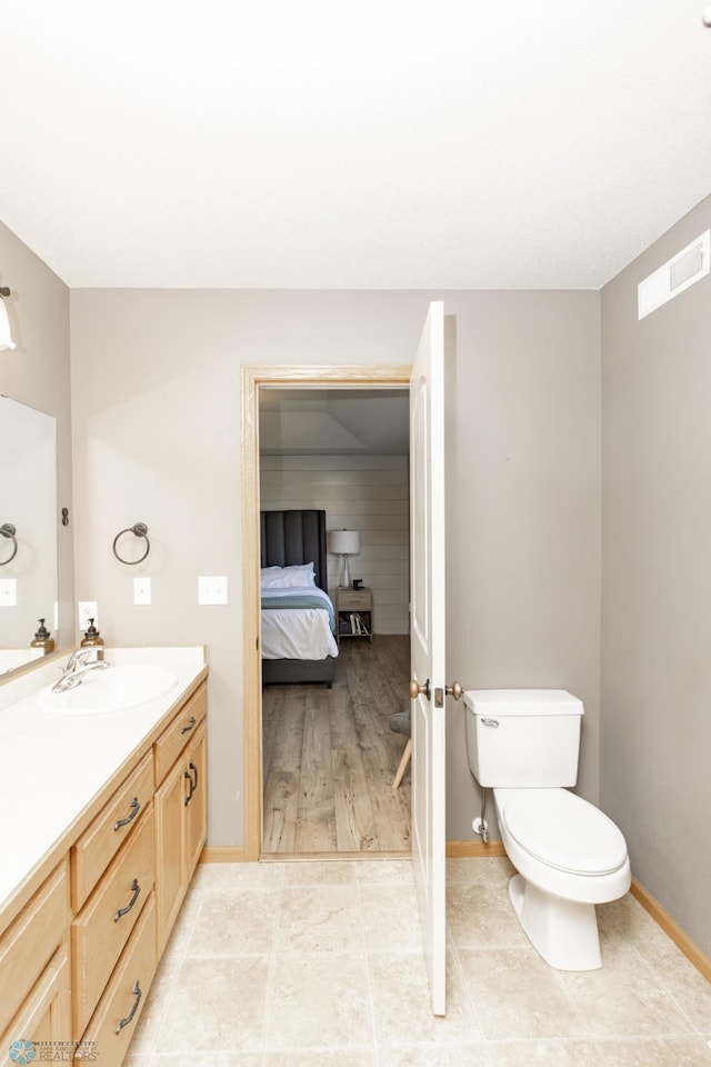 bathroom with toilet, baseboards, visible vents, and vanity