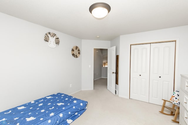 bedroom featuring baseboards, light colored carpet, and a closet