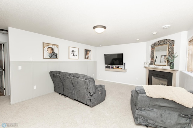living area with wainscoting, carpet flooring, and a glass covered fireplace