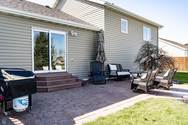 rear view of property featuring entry steps, fence, a shingled roof, and a patio area
