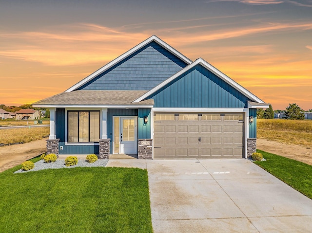 craftsman-style house featuring a lawn, roof with shingles, an attached garage, and stone siding