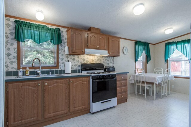 kitchen with a sink, a textured ceiling, range with gas stovetop, light floors, and under cabinet range hood