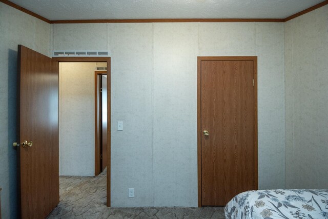 bedroom with carpet floors, ornamental molding, and a decorative wall