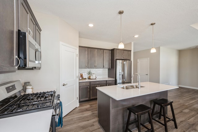 kitchen with a sink, appliances with stainless steel finishes, backsplash, and dark wood finished floors