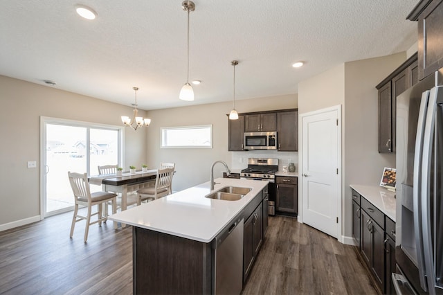 kitchen featuring dark brown cabinets, dark wood-type flooring, a sink, a notable chandelier, and stainless steel appliances