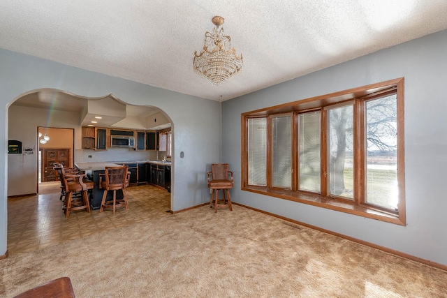 dining area with arched walkways, baseboards, a notable chandelier, and a textured ceiling
