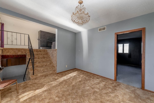 unfurnished living room with visible vents, baseboards, a textured ceiling, a chandelier, and carpet