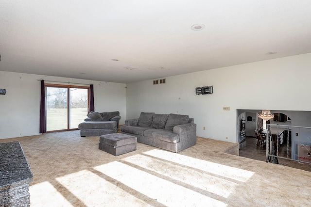 carpeted living room featuring visible vents and an inviting chandelier