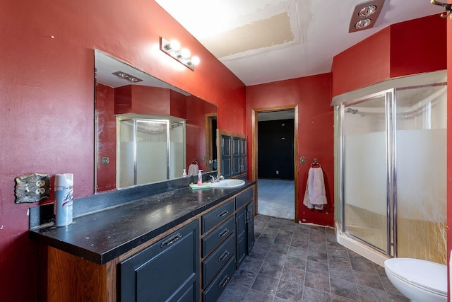 full bathroom featuring vanity, stone finish floor, toilet, and a shower stall