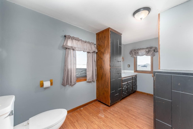 bathroom with baseboards, wood finished floors, toilet, and vanity